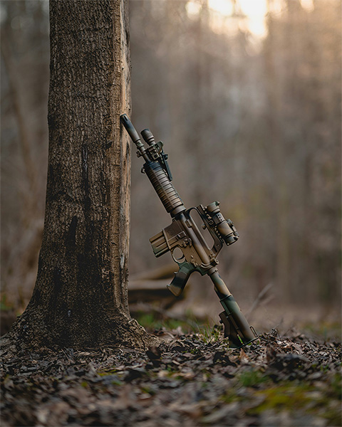 Assault rifle leaning against a tree