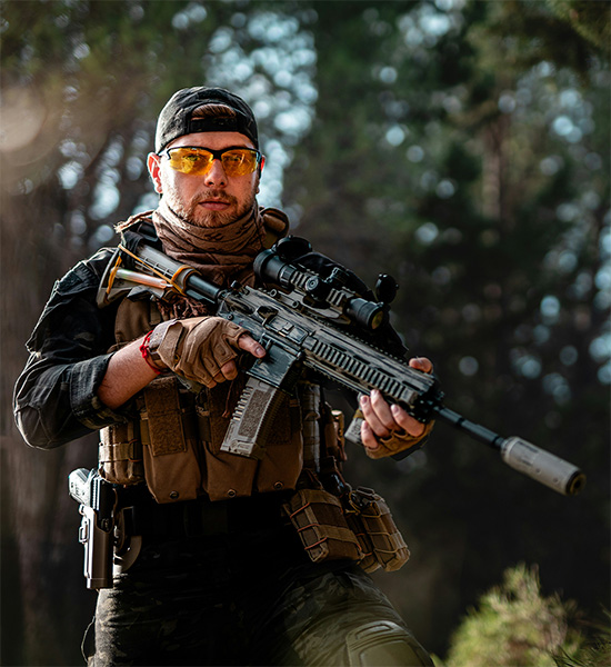 man dressed in tactical attire holding a silenced weapon